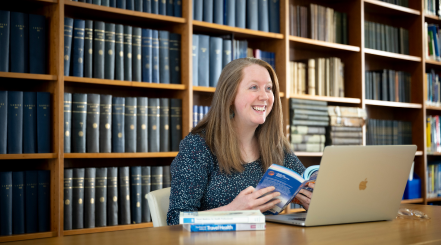 A woman studying in a library with a laptop